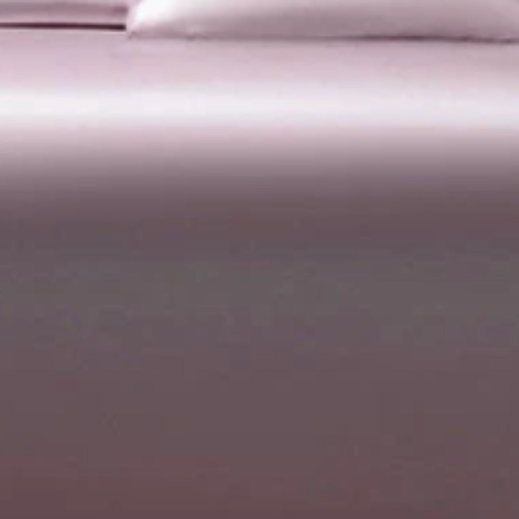 A close-up of a smooth, solid-colored fabric surface in a muted mauve or dusty purple tone, with a soft lighter area at the top edge.