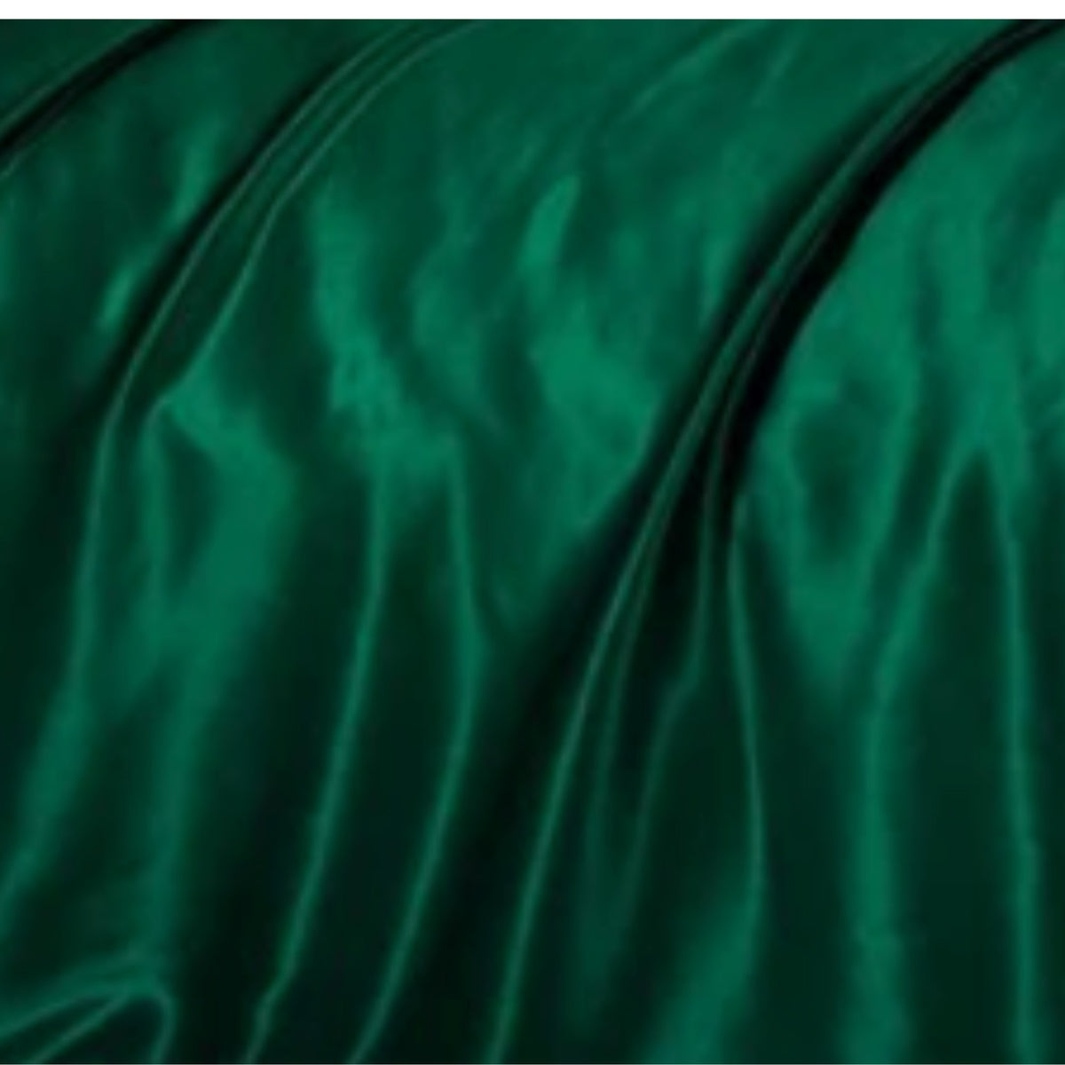 A close-up of draped emerald green silk fabric with soft folds and a subtle sheen.