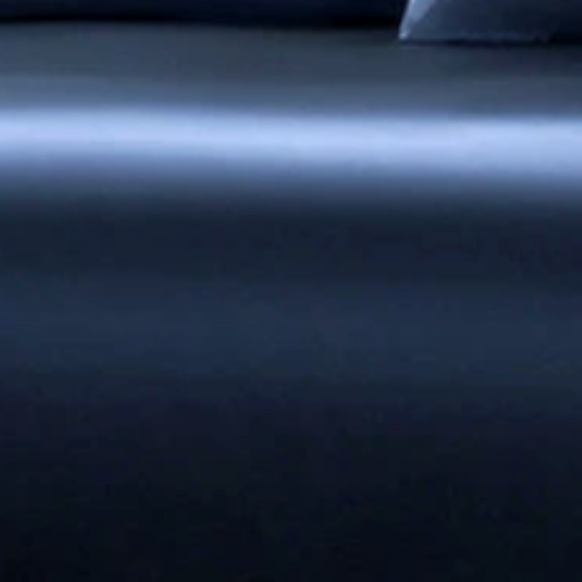A close-up of a dark navy blue fabric surface with a soft horizontal light reflection across the middle.