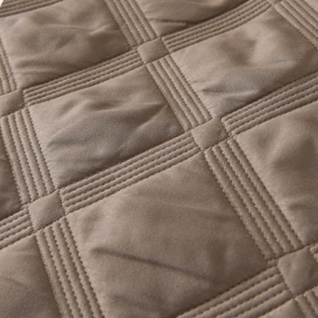 Close-up of a quilted fabric surface in a warm taupe-beige color, showing stitched square panels and stitched border lines.
