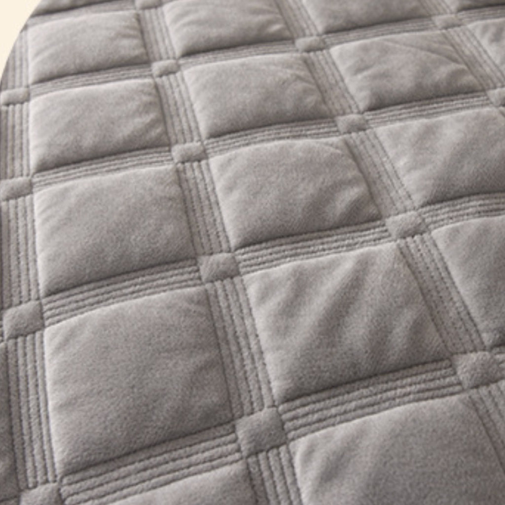 Close-up of a gray quilted fabric surface with stitched square panels and raised seam lines.