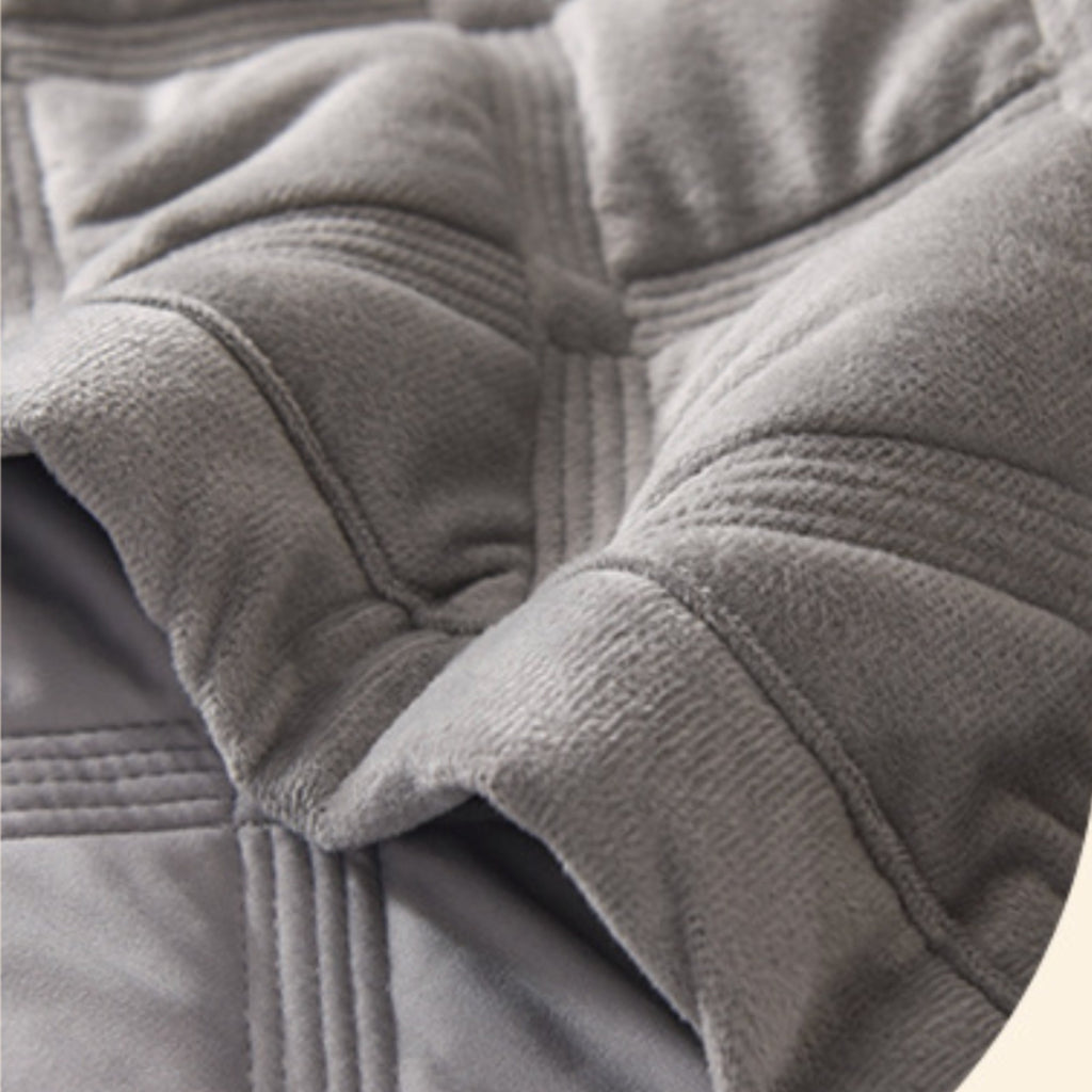 Close-up of a gray quilted fleece or sherpa fabric with stitched paneling and soft folds.