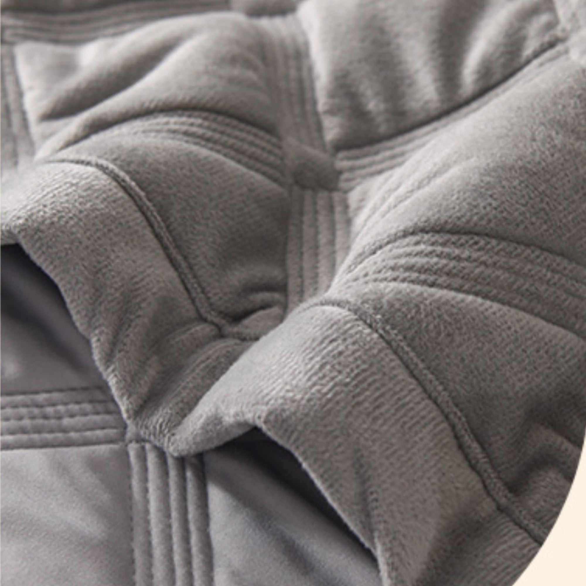 Close-up of a gray quilted fleece or sherpa fabric with stitched paneling and soft folds.