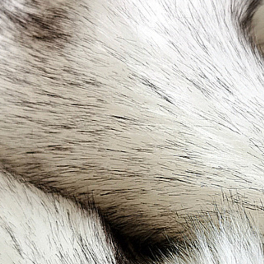 A close-up texture shot of fluffy faux fur fabric, showing strands of white, light gray, and black.