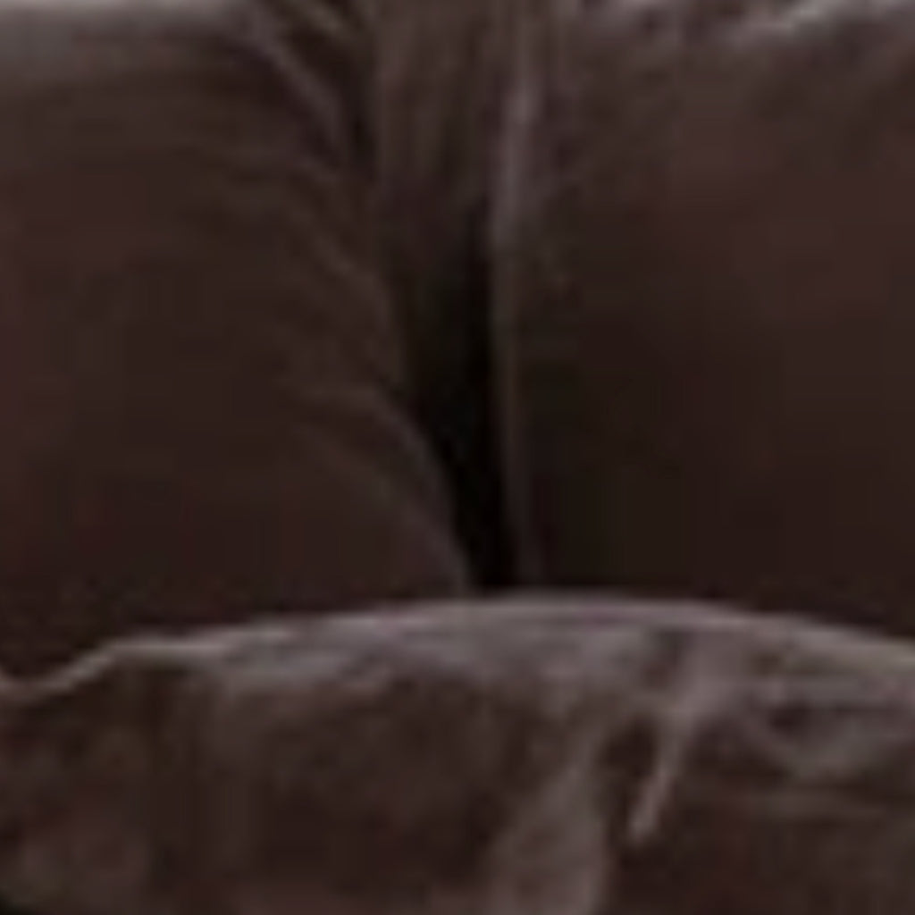 A close-up view of a dark brown textured fabric, likely a sofa or cushion, with soft folds and a slightly blurred, low-resolution appearance.