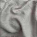 A close-up of draped light gray fabric with a soft woven texture and subtle folds.
