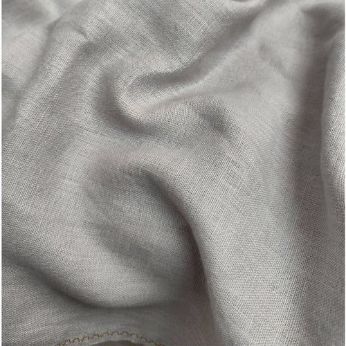 A close-up of draped light gray fabric with a soft woven texture and subtle folds.