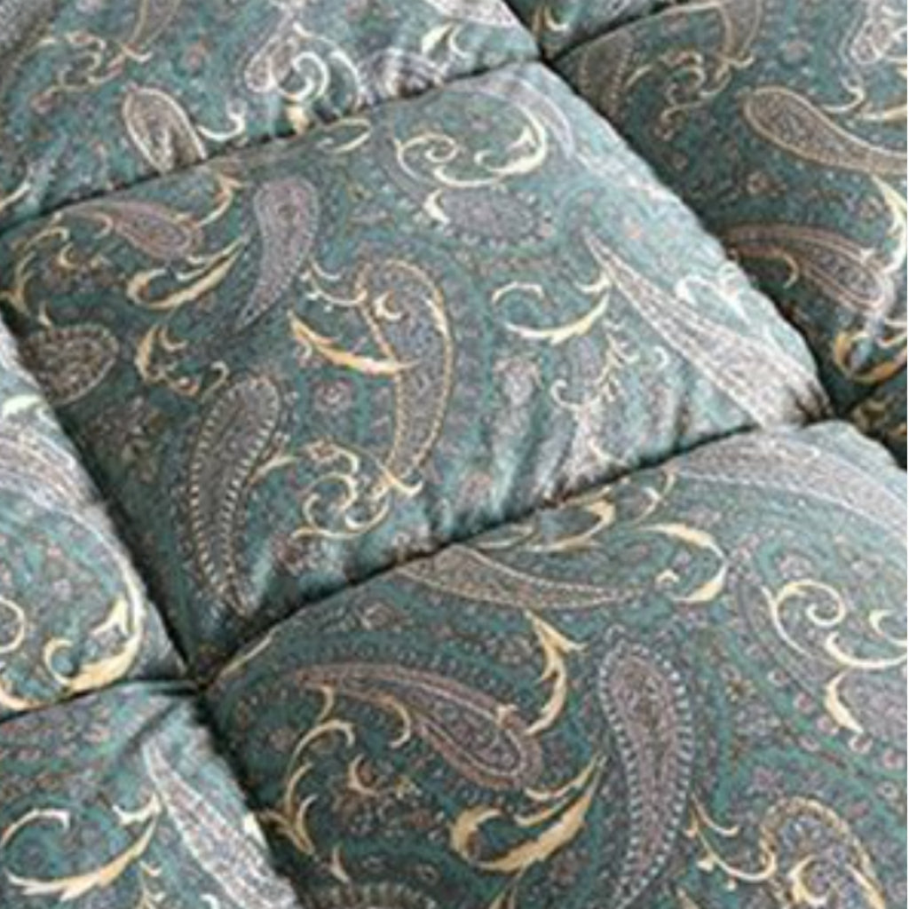Close-up of a quilted cushion or upholstered panel with a teal-green background and an ornate paisley pattern in beige, gray, and muted blue.