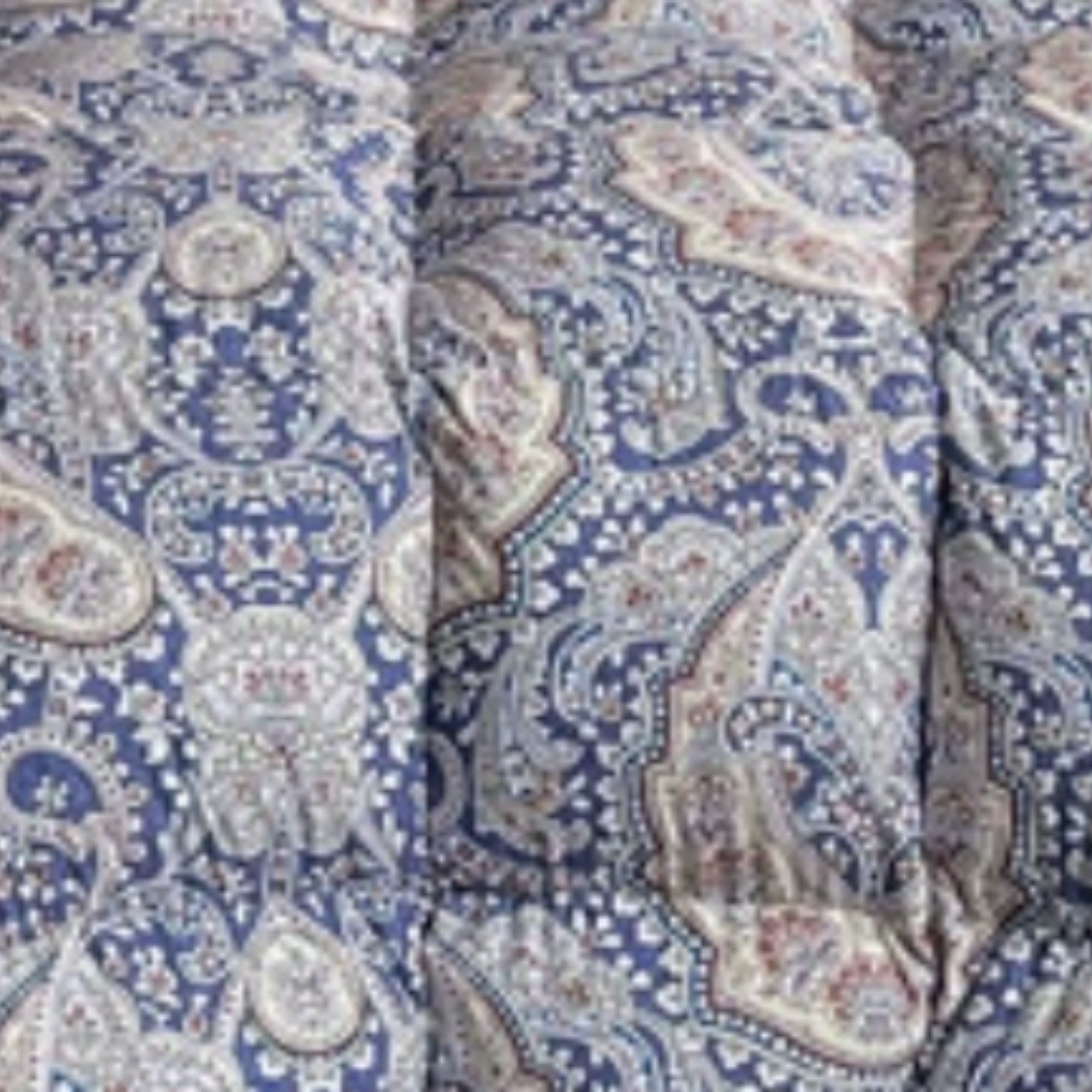 A close-up of a quilted comforter or duvet with a detailed paisley pattern in blue, beige, and white.