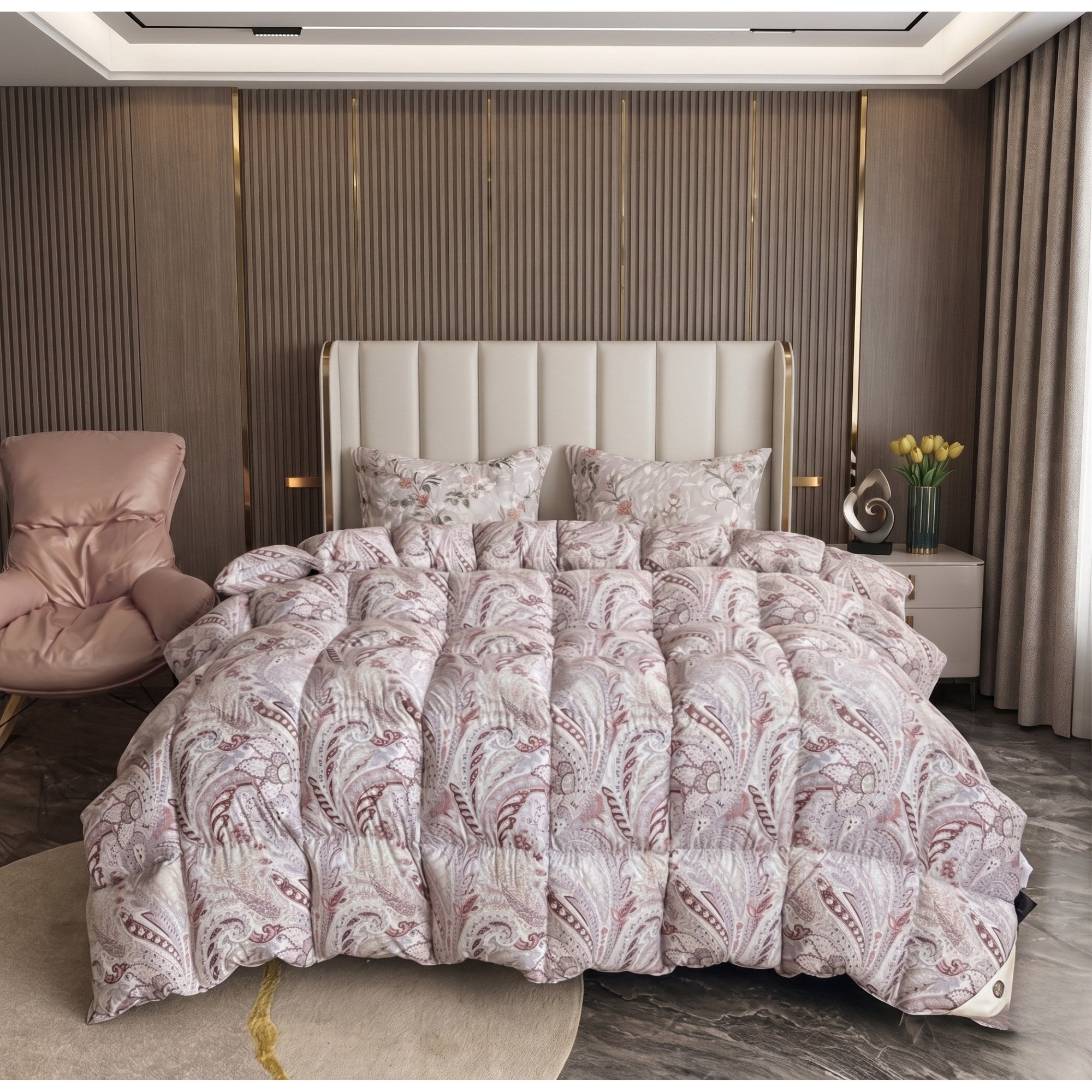 A plush quilted comforter set with matching pillowcases featuring a dusty pink and beige paisley pattern, styled on a bed in a modern bedroom with a tufted headboard, slatted wood wall, and a pink armchair.
