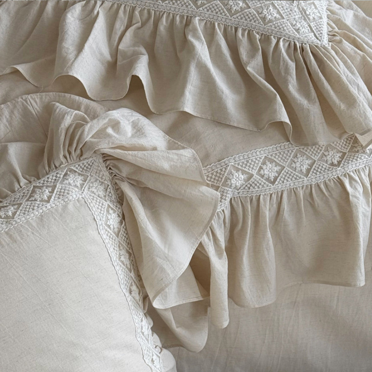 Close-up of a cream-colored ruffled fabric with delicate white embroidered detailing along the ruffles.