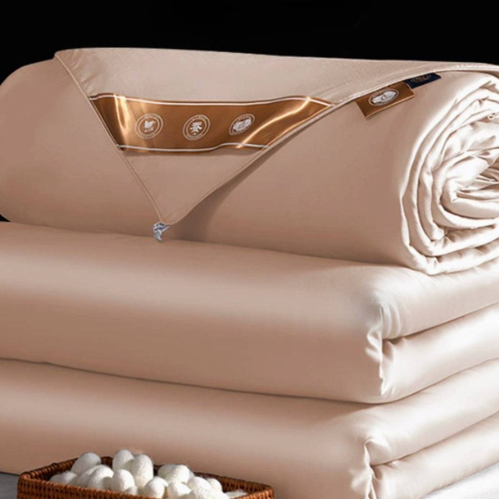A stack of folded and rolled dust pink silk filled duvet 